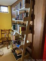 Side view of the white painted bookshelf with books and DVDs placed on shelves against a wood-paneled wall in a basement.