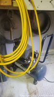 Side view of Mastercraft air compressor with yellow air hose coiled and hanging in front of it.
