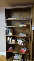 Front view of solid wood 4-shelf bookcase with books and games on shelves.