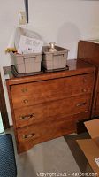 Front view of the dresser showing three drawers, vintage brass hardware, and wood grain finish with minor signs of wear.