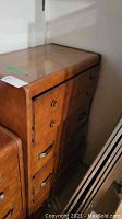 Side view of the dresser showing four drawers with different handle types and the wood finish.
