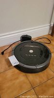Roomba 880 vacuum unit positioned next to charging base on tiled floor