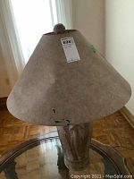 Photo of ceramic elephant base lamp showing large conical shade with visible damage including tears and discoloration.