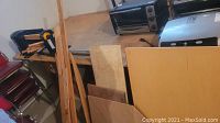 Lathe setup showing assorted wood pieces including planks and sheets leaning against a table.