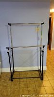 Front view of the collapsible metal clothes drying rack showing silver horizontal bars and black frame.