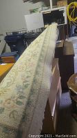 Side view of the rug showing the floral pattern and the edge condition while rolled on boxes.