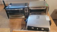 Paterno and Cuisinart toaster ovens alongside a George Foreman Lean Fat Grilling Machine on a wooden surface
