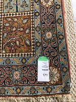 Close-up of rug corner showing floral and geometric border with a lot number tag.