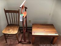 Photo showing wooden chair, clothing stand, and small side table against corner wall.