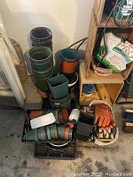 Overview of plastic plant pots of various sizes stacked vertically along with wooden crates and garden gloves in baskets nearby.