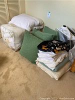 Photo showing queen duvet storage bag, green cushions, folded linens and black printed blanket.