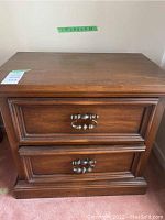 Wooden night stand front view showing two drawers, metal handles, dark brown finish, and surface scratches.