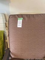 Close-up of brown cushioned chair showing fabric texture and condition.