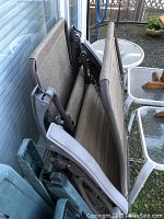 Photo showing two folded gravity lounge chairs leaning against a wall.
