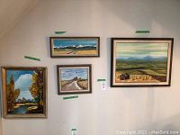 Four landscape paintings hanging on a wall, each in a wood frame, showing different rural and mountainous scenes.