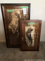 Two framed vintage-style pictures leaning against a wall, one large and one medium size. Both depict women in sepia tones.