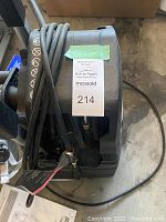 Top view of black electric pressure washer showing power cord and hose reel, with a MaxSold tag attached.