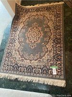 Traditional floral patterned rug with beige, blue, and peach colors, showing fringed edges and detailed pattern.