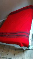 Full view of blanket spread out showing red color and black stripes at the ends.