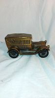Right side view of antique metal model car coin bank showing detailed grill, hood, cargo area and wheels.