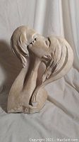 Front-side view of the sculpture showing the couple's faces close, details on hair and facial features visible.