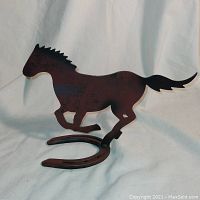 Side view of the metal horse silhouette statue showing horse shape and horseshoe base with distressed paint finish.