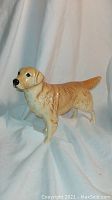 Side view of the Labrador dog figurine showing tan and cream coloring, tail straight out, and detailed texture.