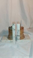 Two marble bookends with antique column design viewed from the side showing height and shape.