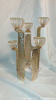 Front angled view of metal candleholder with five glass holders on textured geometric base.