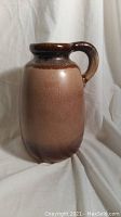 Photo of the vintage pottery jug from one side showing the brown glaze and handle.