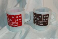 Pair of vintage Anchor Hocking USA milk glass mugs with dice design, one red and one brown, shown from front angle.