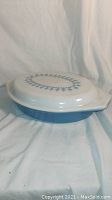Side view of the blue divided casserole dish with white lid showing garland and snowflake design.