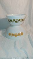 Pair of vintage Pyrex mixing bowls stacked, showing floral patterns and shape.