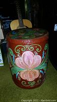 Front view of antique hand painted wooden barrel showing detailed pink flower and green and blue floral patterns.