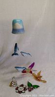 Overall view of ceramic whale wind chime showing sky design and dangling whale pieces with glass decor items below