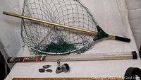 Fishing rod in its tube labeled MonoCarbon by Daiwa, fishing weights, and reel placed on white cloth