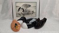 Full lot with rosewood duck, loon coin bank, terracotta duck dish, and framed Sam Lu Canada Geese print