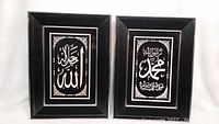 Front view of two framed Islamic calligraphy artworks with Allah and Muhammad inscriptions in black and white with silver accents.