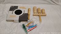 Photo showing the Remo Practice Tunable Drum Pad in original box, the wooden percussion instruments (guiro scraper, triple tone blocks on handle), small mallet, and a sealed pack of colorful plastic kazoos.