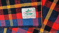Close-up photo showing the Plessis Sportsman label on the blanket with the plaid pattern.
