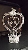Frontal view of spun glass decoration showing the two swans at the base and the two love birds inside inner heart with bells at the top of outer heart frame.