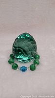 Photo of green faceted crystal egg surrounded by green bead bracelet with blue bead accent, showing overall lot contents.
