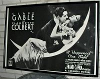 Large framed black and white vintage movie poster for It Happened One Night starring Clark Gable and Claudette Colbert, showing the iconic image of the couple on a crescent moon with starry background.