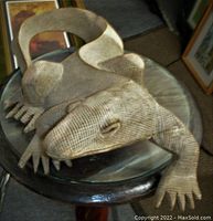 Top front angled view of carved wooden Komodo dragon sculpture showing detailed texture and shape.