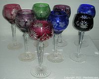 Eight coloured glass goblets arranged on a white Styrofoam platform