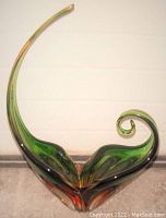 Front view of the sculptural glass bowl showing the curled spiral design and strong green and amber coloration.