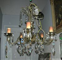 Front angle showing the chandelier with five light holders, hanging crystal prisms, wired ceiling cap and visible discoloration on candle sleeves.