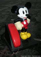 Side view of vintage Mickey Mouse phone showing red handset and Mickey Mouse figure.
