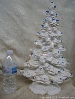 Full front view of ceramic tree lamp next to water bottle for scale