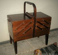 Closed view of sewing cabinet showing dark wood finish and carry handle